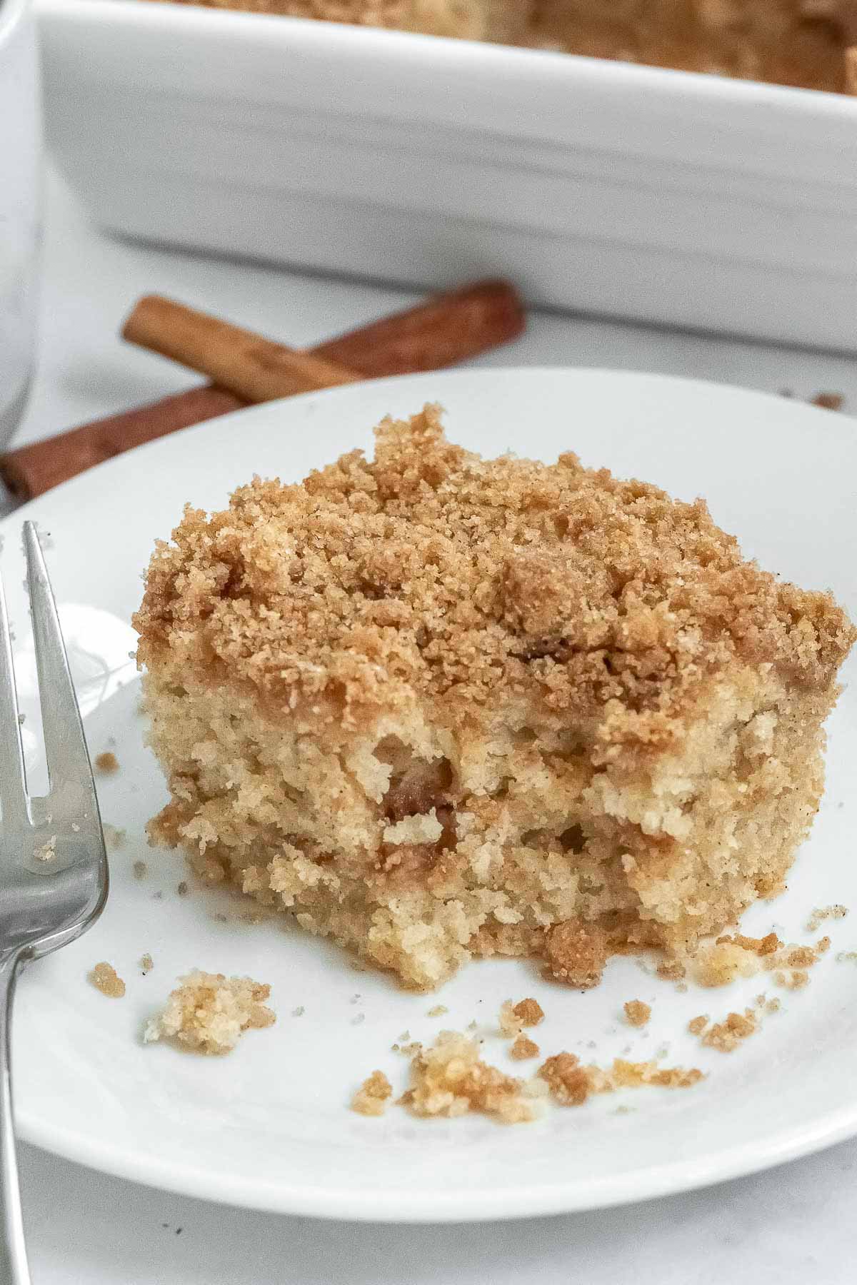 piece of coffee cake with crispy topping on a white plate with a fork