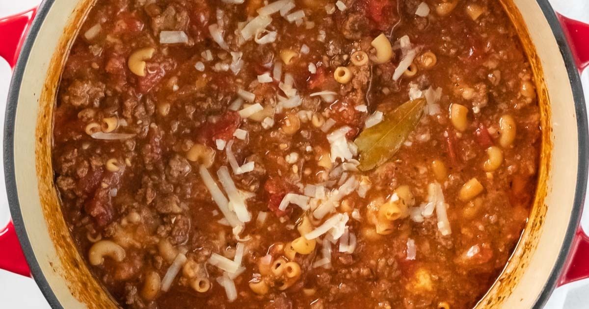 Close up on a pot of goulash filled with tomato sauce, ground meat and elbow noodles with cheese cooking.