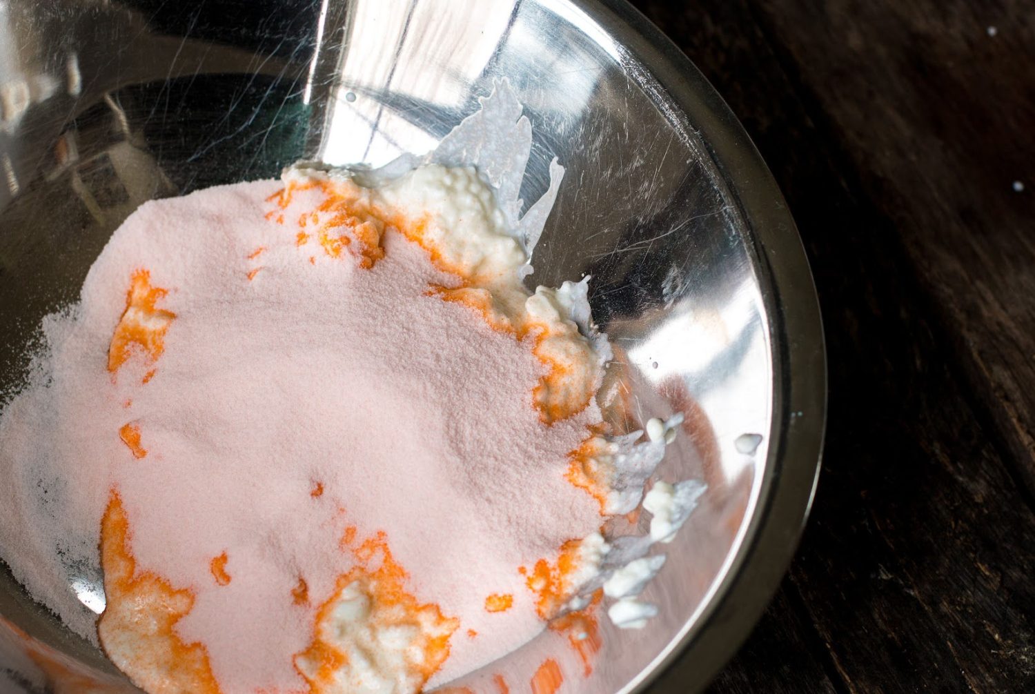 orange jello powder sprinkled over the cottage cheese in a stainless steel bowl.