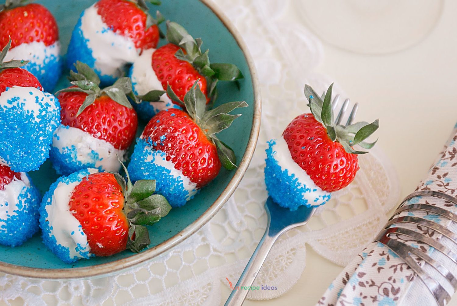4th of july strawberries in a serving bowl and one on a fork.