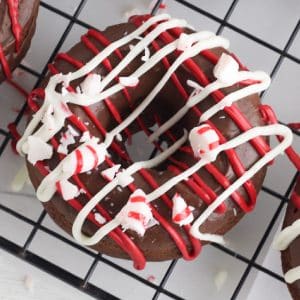 Chocolate cake donut on a wire rack decorated with peppermint and white and red chocolate.