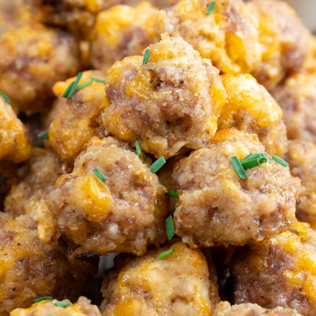 A close up of sausage cheese balls garnished with freshly chopped chives. 