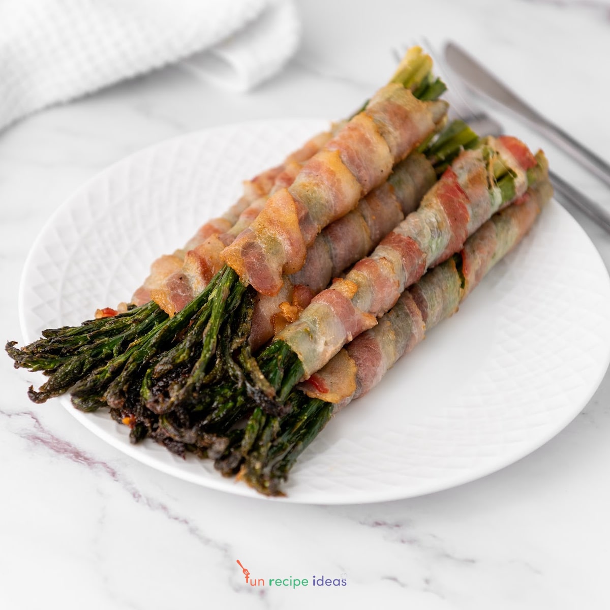 bacon wrapped asparagus on a white plate.
