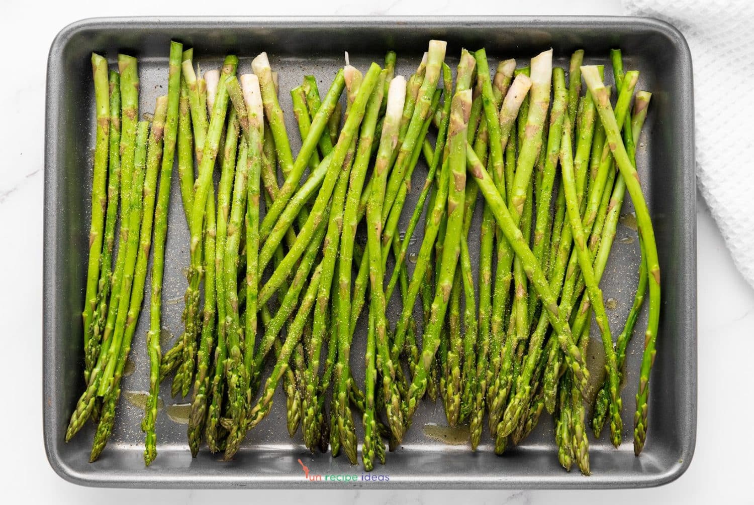 seasoned asparagus on a baking sheet.