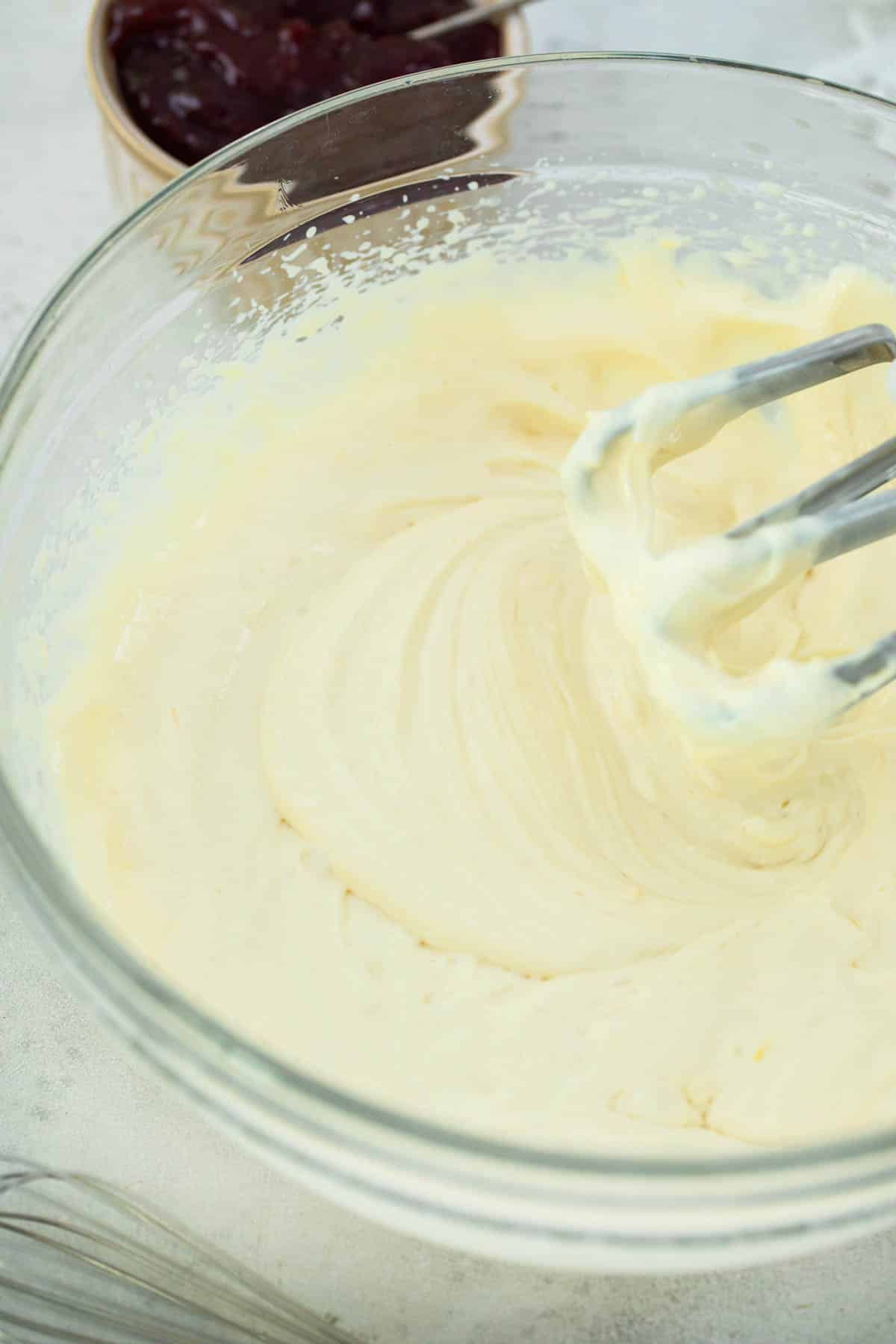 Cream cheese mixture in a clear glass bowl with beaters