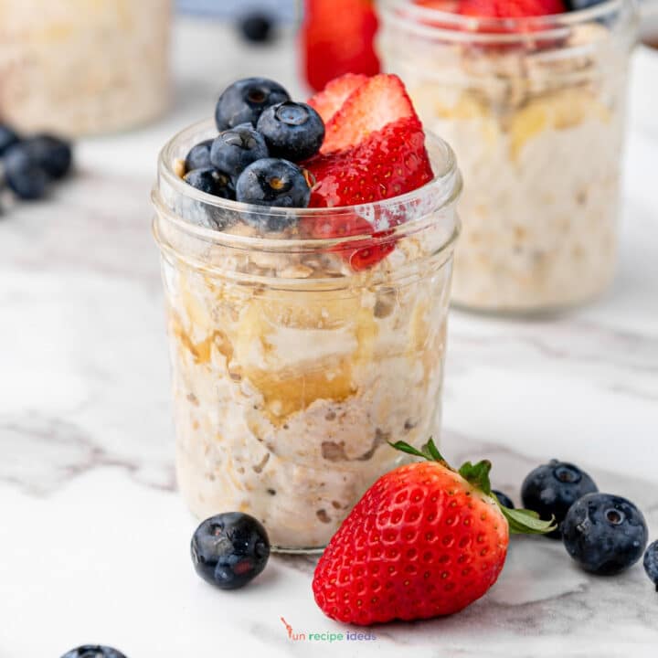 overnight oats in a jar with strawberry and blueberry garnishes.