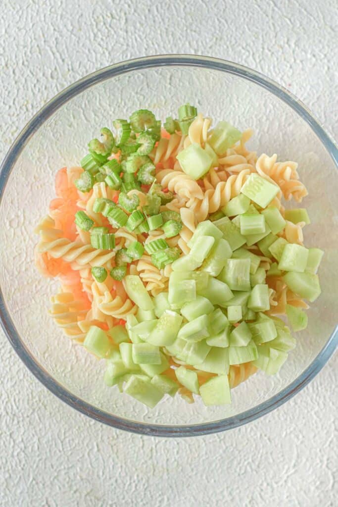 celery, cucumber and pasta in glass mixing bowl