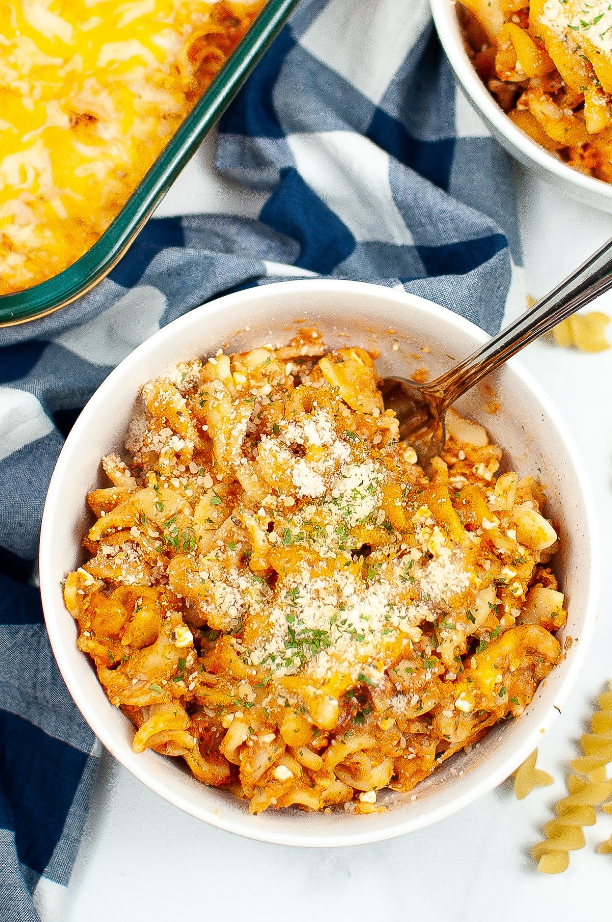 Cheesy rotini bake in a bowl form overhead topped with parmesan cheese.