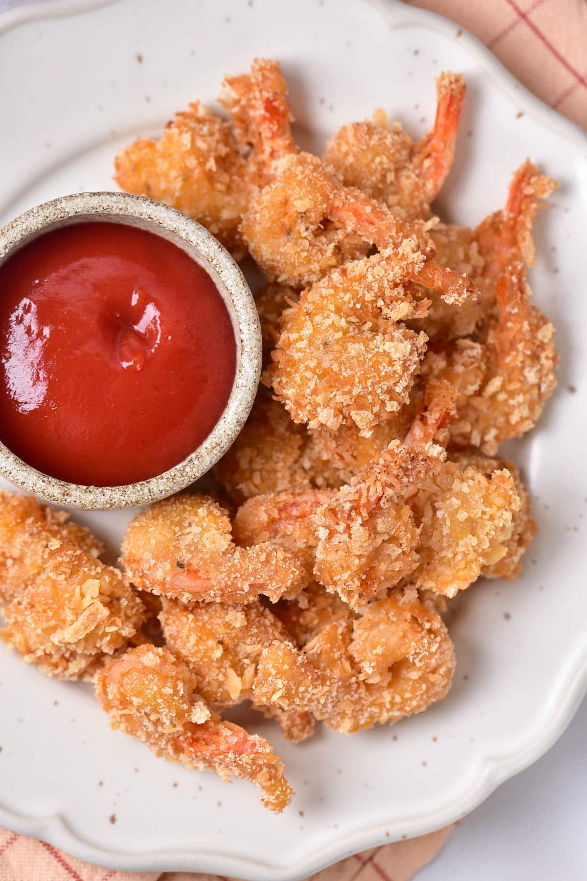 Coconut shrimp with red dipping sauce on a white speckled plate