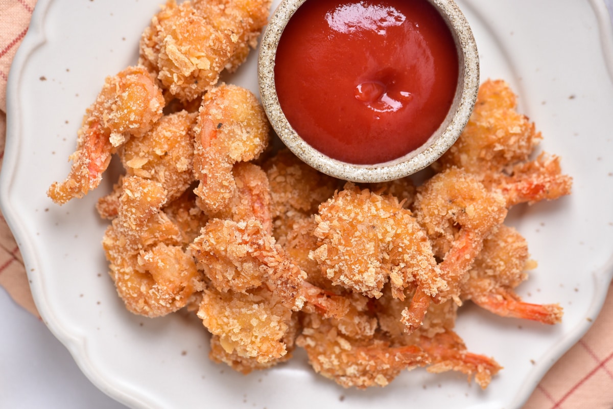 Coconut shrimp on speckled white plate with dipping sauce