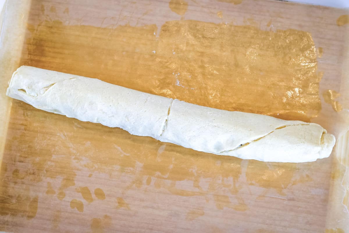 a roll of dough on a cutting board.