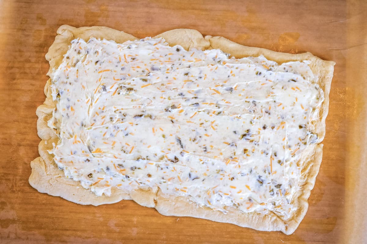 filling spread on a sheet of dough on a cutting board.