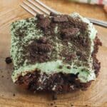 grasshopper brownie recipe with brownie base, green creamy layer and topped with chocolate cookie crumbles on top.