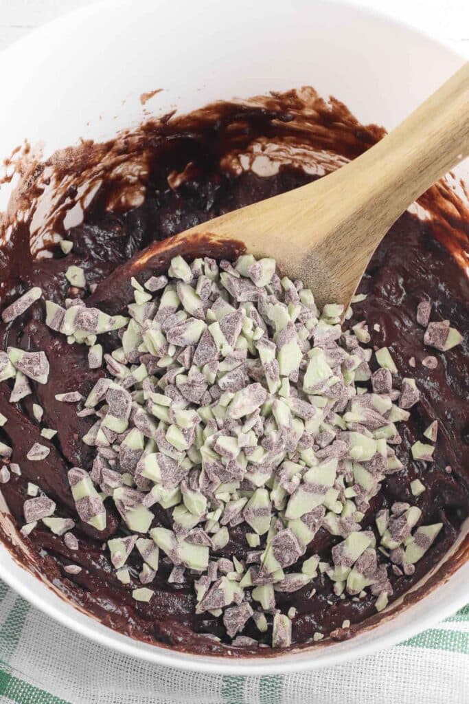 brownie batter in a white bowl with mint chips on top.