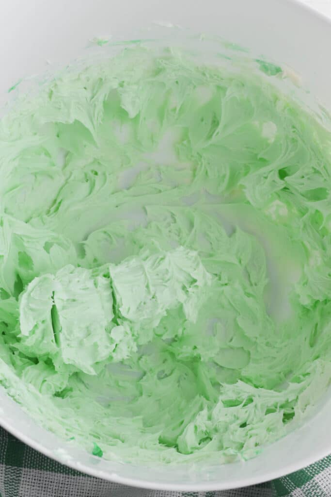 green colored frosting in a white mixing bowl.