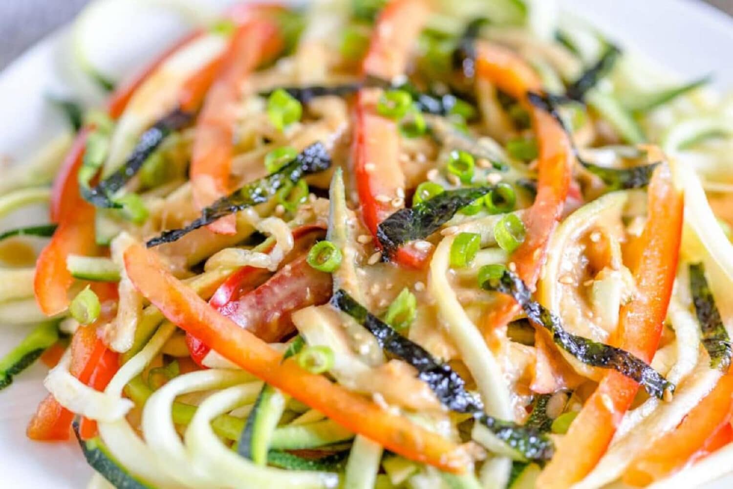 Japanese zucchini noodle salad mixed with other shredded vegetables and dressing on a plate.